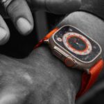 Close up of an orange Apple Watch Ultra on a man's arm.