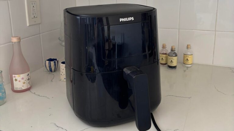 A black plastic spatula with a silver handle on a wood surface.